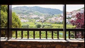 Ein Steine Balkon mit Blick auf eine Hügelstadt und Weinberge.