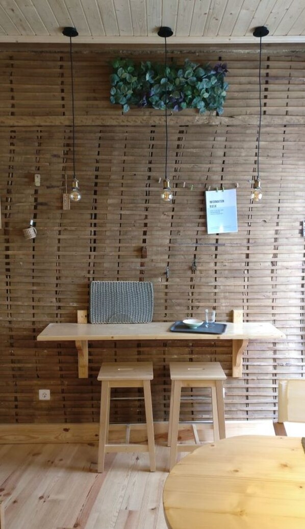 Un interior de madera con una mesa larga, dos taburetes y lámparas colgantes.