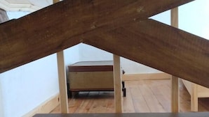 A room with a wooden ceiling and a bed in the background.