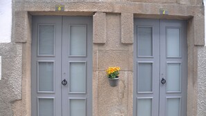 Two grey double doors with frosted glass panels, each marked with a number (6 and 4). A small planter with yellow flowers is attached to the wall between the doors.
