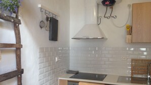 Une cuisine avec des carreaux de céramique blancs disposés en motif métro, une hotte de cuisine en acier inoxydable et des armoires en bois.