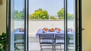 A balcony with a table set for breakfast, including plates, glasses, and a pitcher.
