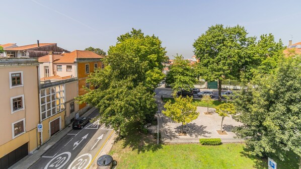A street view with a parking area, trees, and buildings. - Terrace Pool Apartment Oporto by LovelyStay (Porto)