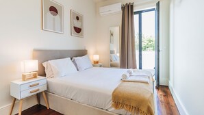 Un dormitorio ordenado con una cama, mesitas de noche y una ventana con cortinas.