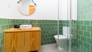 A bathroom with a wooden vanity, a round mirror, a white sink, and a toilet. - Urban House Marquês - F - by LovelyStay (Porto)