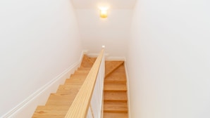 A wooden staircase with white walls and a light fixture at the top. - Urban House Marquês - F - by LovelyStay (Porto)