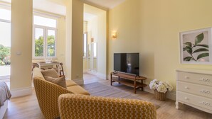 Ein geräumiges Wohnzimmer mit einer Sofagarnitur, einem Flachbildfernseher und einer Essecke mit Tisch und Stühlen.