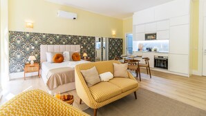 Una habitación de hotel con cama, sofá, mesa de comedor y kitchenette.