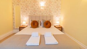 A neatly made bed with two pillows, two bedside tables with lamps, and a floral wallpaper. - Urban House Marquês - C - by LovelyStay (Porto)