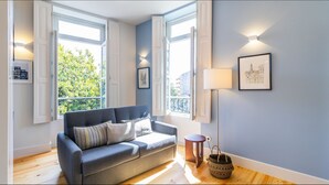 A modern living room with a grey sofa, a floor lamp, and a framed picture on the wall. - Barros Lima 493: Apt 2 by LovelyStay (Porto)