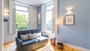 A modern living room with a grey sofa, a floor lamp, and a framed picture on the wall.