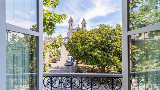 A view from a window overlooking a street with a church and a tree. - Barros Lima 493: Apt 2 by LovelyStay (Porto)