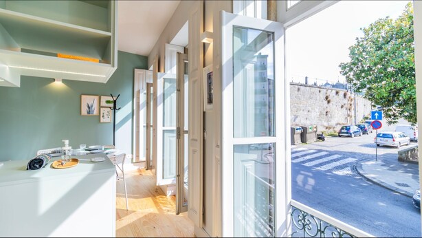 Una habitación de hotel moderna con balcón, vista a la calle y al paisaje urbano.