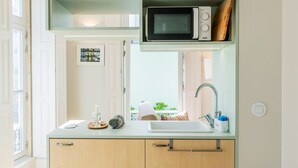 Una cocina moderna con microondas, pileta y ventana con vista a follaje.