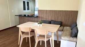 Un espacio habitable compacto con una mesa de comedor, dos sillas, un sofá y una pequeña zona de cocina.
