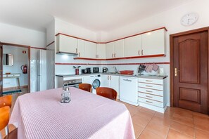 Enjoy meals at the dining table with oven, microwave, and washing machine nearby.