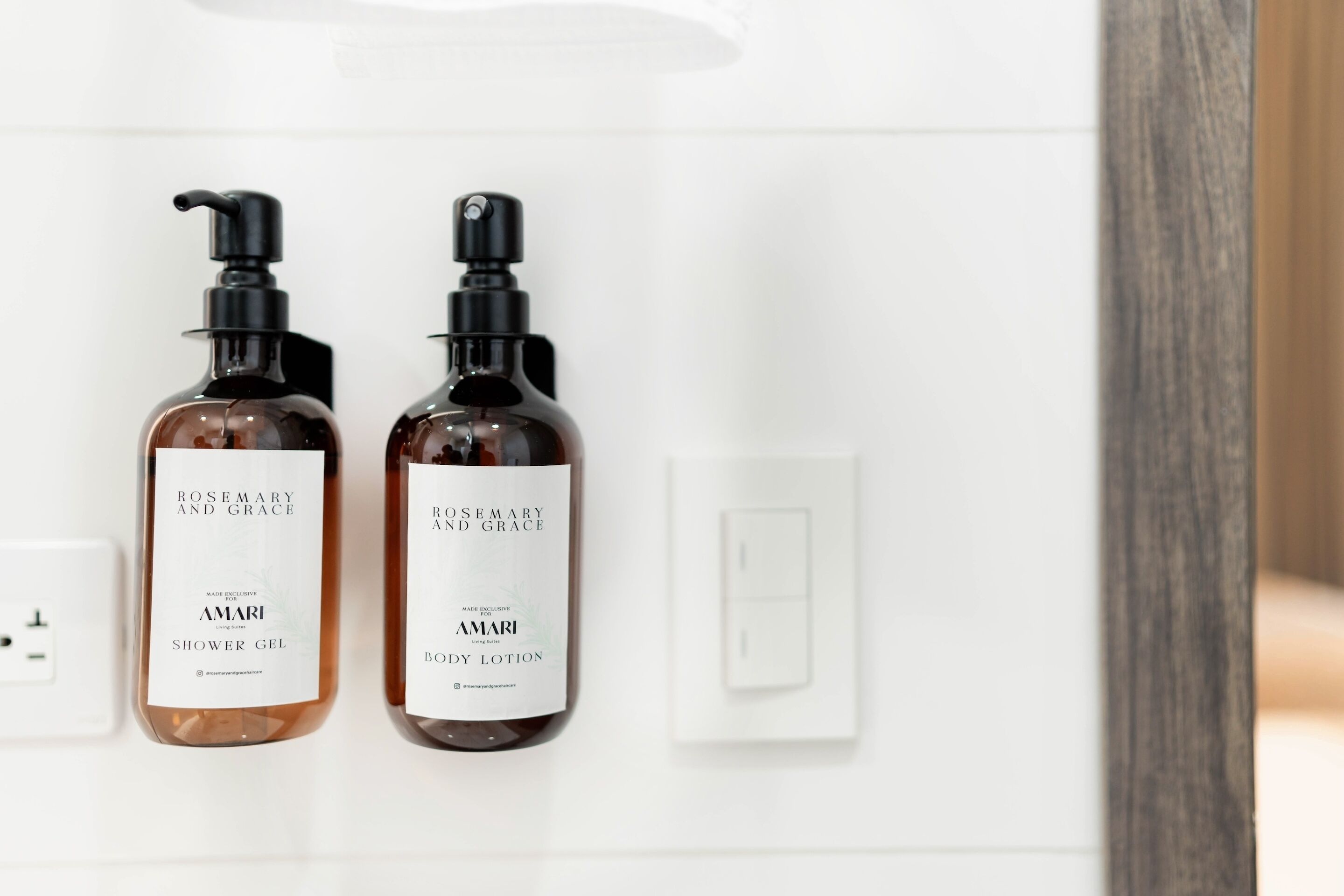 Two bottles of Amari body lotion and shower gel on a white shelf.