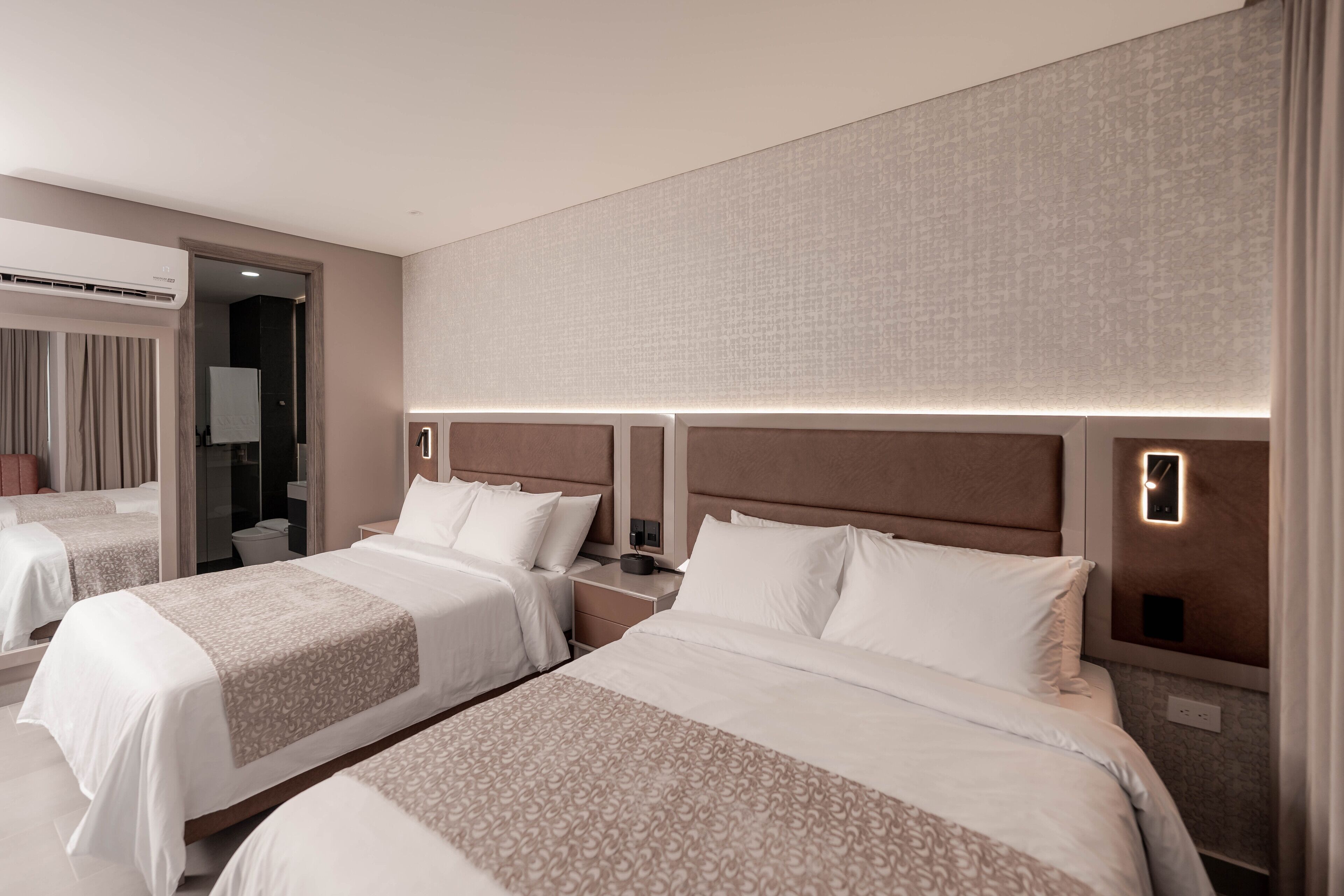 A hotel room with two beds, a large mirror, and a modern design.