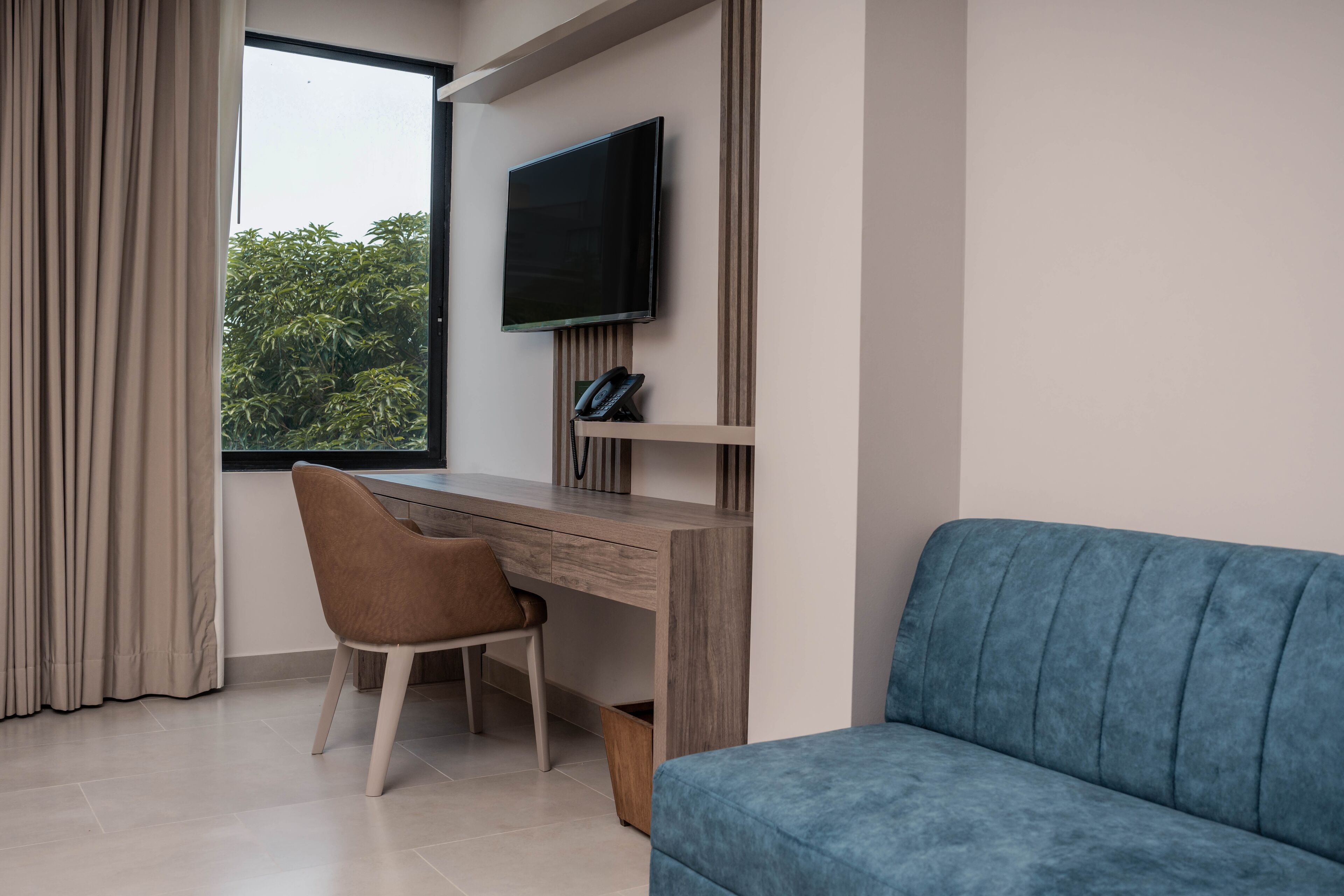 A modern room with a desk, chair, and a blue sofa.