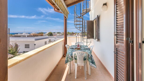 Ein Balkon mit Tisch und Stühlen, eine Wendeltreppe und Blick auf die Stadtlandschaft.