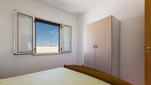 Ein Schlafzimmer mit Bett, Kleiderschrank und Fenster mit Blick zum Himmel.