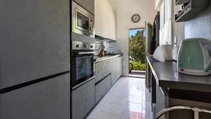 A modern kitchen with stainless steel appliances, a clock on the wall, and a view of greenery outside. - 3547 Casa di Margherita by Barbarhouse (Manduria)