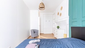 Une chambre à coucher avec un lit, une chaise, une commode et une porte.