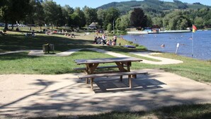 Un parc au bord du lac, avec des tables de pique-nique, des sentiers pédestres et des gens qui se baignent.