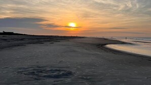 Une plage avec un coucher de soleil en arrière-plan.