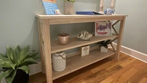 Une console en bois agrémentée d’objets décoratifs, d’un tableau encadré et d’une petite plante en pot.