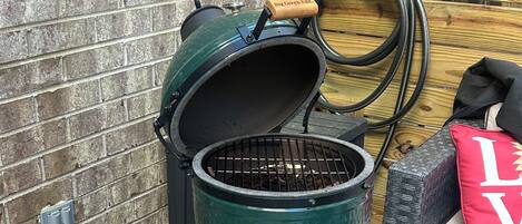 A portable grill with a lid open, placed on a stand in an outdoor setting.