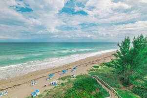 A beach with a wooden walkway, beach chairs, and umbrellas.