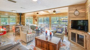 A spacious living room with a large TV, comfortable seating, and a view of a lake. - Kilgore Lakefront Home w/ Private Dock & Pier! (Kilgore)