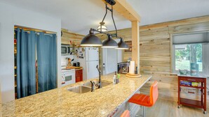 A kitchen with granite countertops, a sink, and a bar area with a chair. - Kilgore Lakefront Home w/ Private Dock & Pier! (Kilgore)