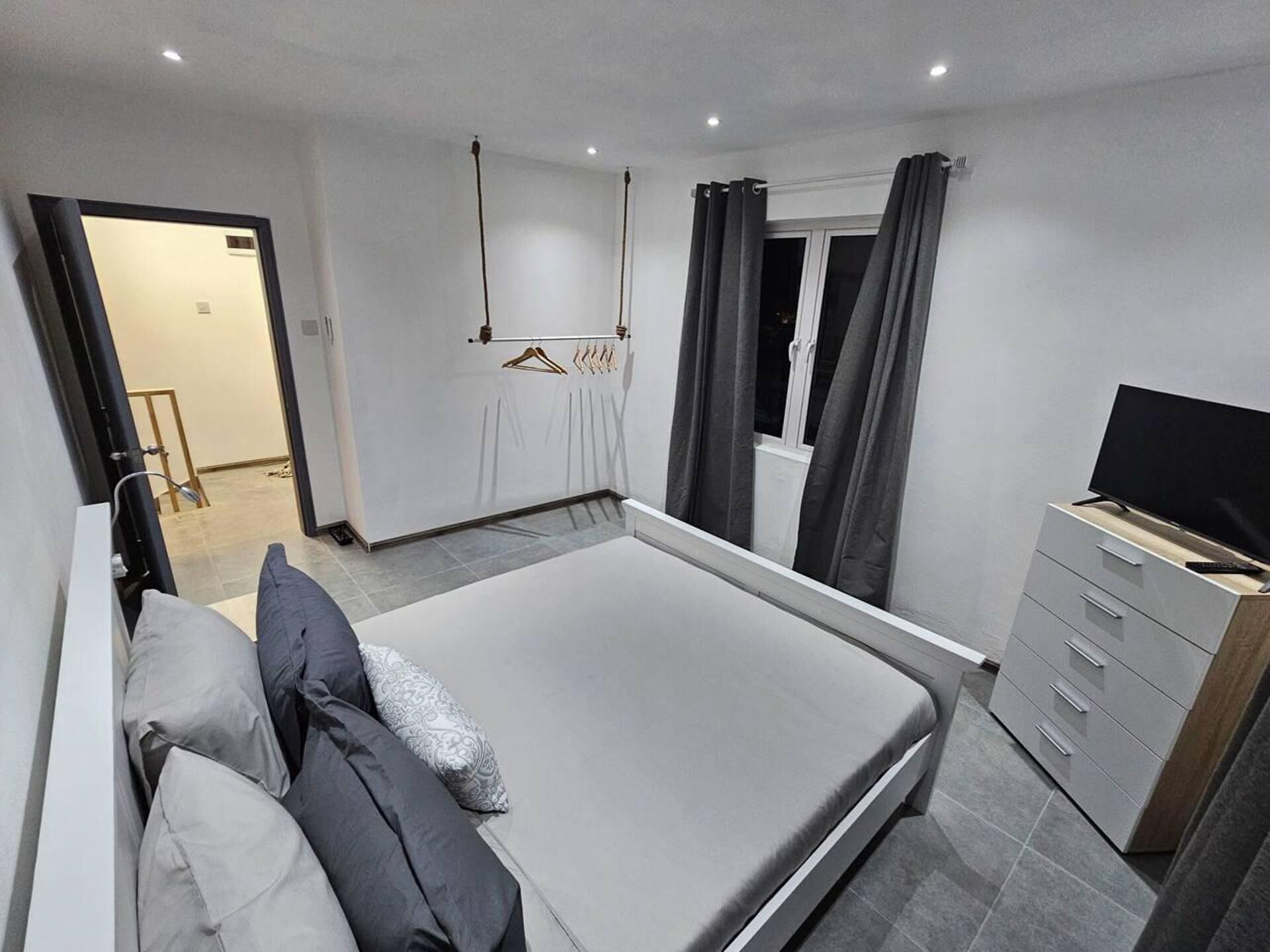 Un dormitorio moderno con una cama grande, un televisor sobre un tocador y un armario.
