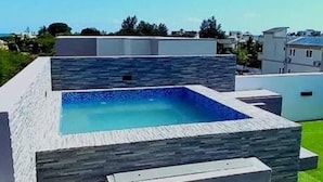 Una piscina moderna al aire libre con un borde de piedra y escalones que la bordean.