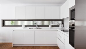 A modern kitchen with white cabinetry, a stainless steel refrigerator, and a window with blinds. - Athenian Riviera Prime Residence  (Vari-Voula-Vouliagmeni)