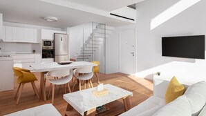 A modern living space with a kitchen, dining area, and a staircase leading to an upper level. - Athenian Riviera Prime Residence  (Vari-Voula-Vouliagmeni)
