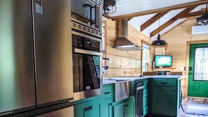 A kitchen with wooden cabinets, a stainless steel refrigerator, and a built-in oven. - ONYX OWL CABIN: Private Hot Tub⁘Fire Pit⁘Heated Patio⁘Vineyard⁘Hiking⁘Golf (Scaly Mountain)