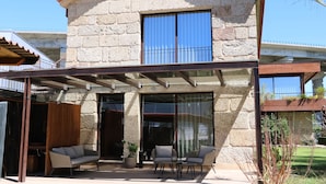 A stone building with a covered patio, outdoor seating, and a view of the surrounding area. - Duas Quintas - Areal Suite Master (Nespereira - GMR)