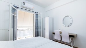A bedroom with a bed, a desk with two chairs, a wardrobe, and a window with curtains. - Midtown Apartment by CorfuEscapes (Corfu)