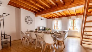 Un comedor con techo de madera, paredes blancas y un gran ventanal con cortinas.