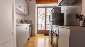Una cocina moderna con electrodomésticos de acero inoxidable, suelo de madera y vistas a un paisaje nevado.