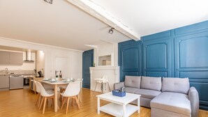 Una sala de estar moderna con un sofá gris, una mesa de centro blanca y una zona de comedor con una mesa y sillas blancas.