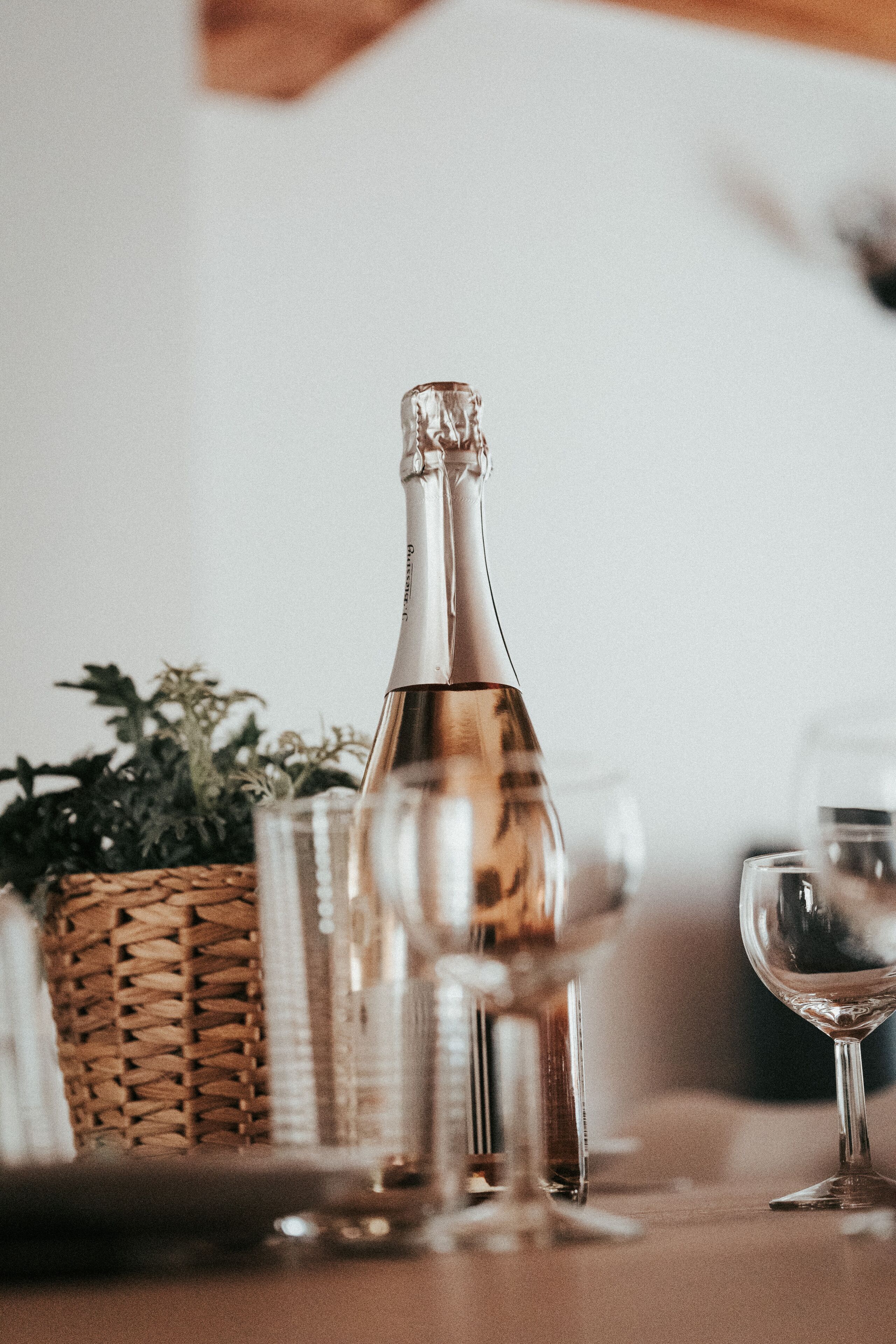Une table dressée avec une bouteille, des verres et un panier tressé.