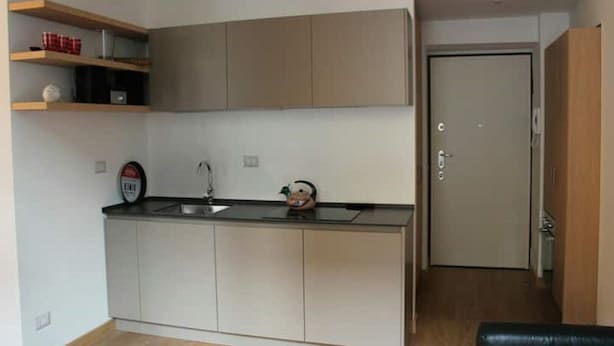 A compact kitchen with a sink, cabinets, and a small countertop. There is a door leading to another room. - Goldoni77. (Milano)