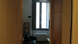 A narrow hallway with wooden doors, a radiator, and a window. - Goldoni77. (Milano)