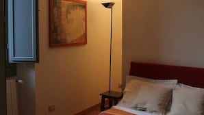 A bedroom with a bed, a floor lamp, and a painting on the wall. - Goldoni77. (Milano)