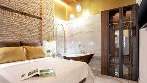 A bedroom with a large bed, a bathtub, and a stone wall. - Genteel Home Catedral 101 (Granada)