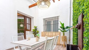 A patio with a wooden table and chairs, a hanging light fixture, and a green wall with plants. - Genteel Home Catedral 101 (Granada)